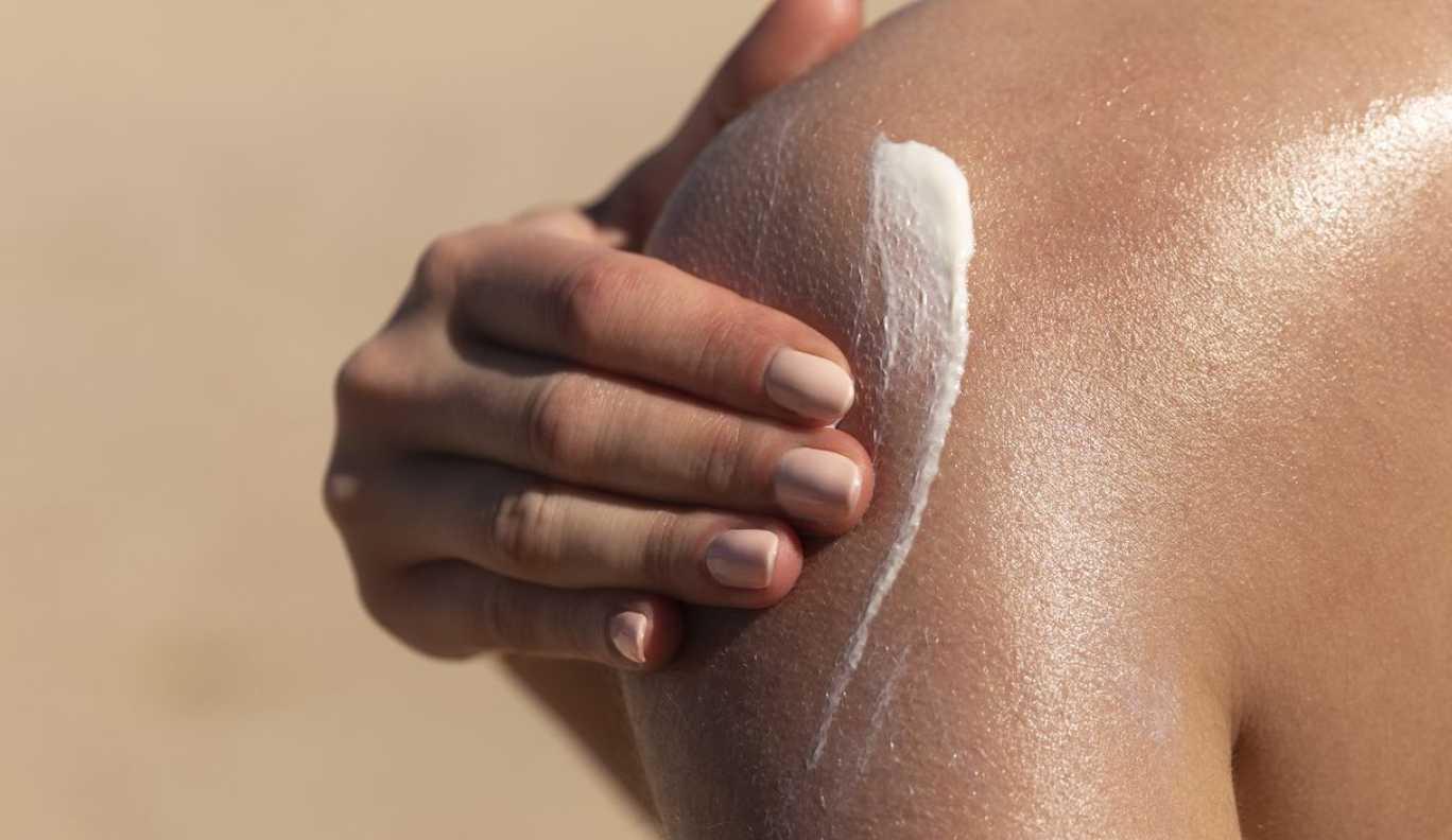 Person applying sunscreen to shoulder